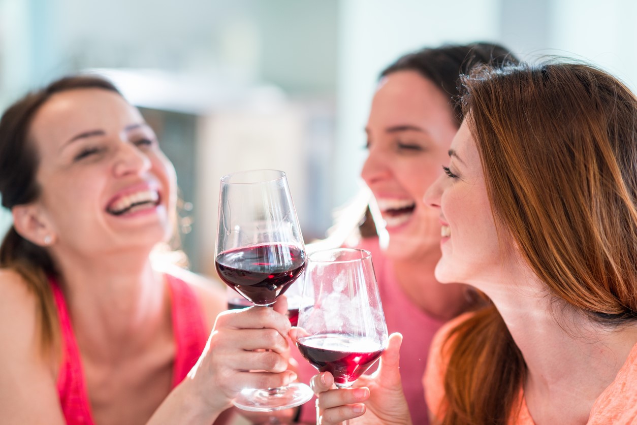 three women drinking wine and laughing